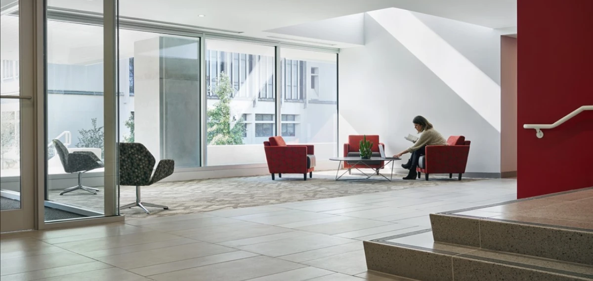 Modern lobby with red chairs and large windows.